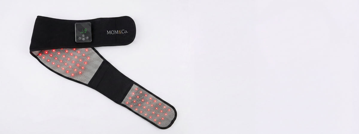 Black wearable heating pad with red LED therapy lights and digital controls on white background